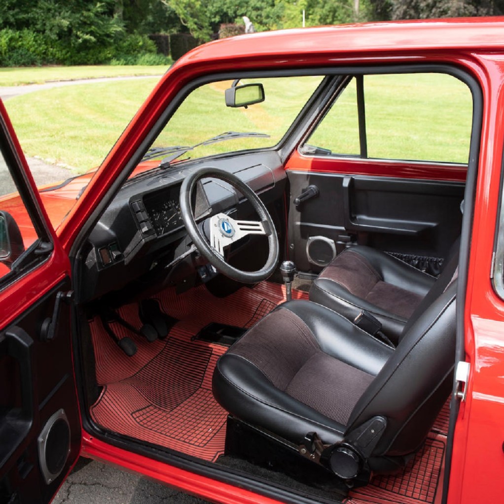 The red-trimmed black front seats and black dashboard of a red 1978 Autobianchi A112 Abarth
