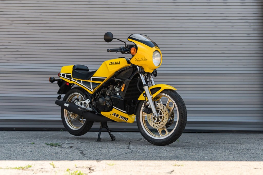 A yellow-and-black 1984 Yamaha RZ350 Kenny Roberts Edition by a garage door