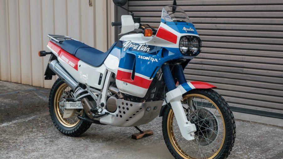 A white-blue-and-red 1989 Honda Africa Twin XRV650 in front of a garage