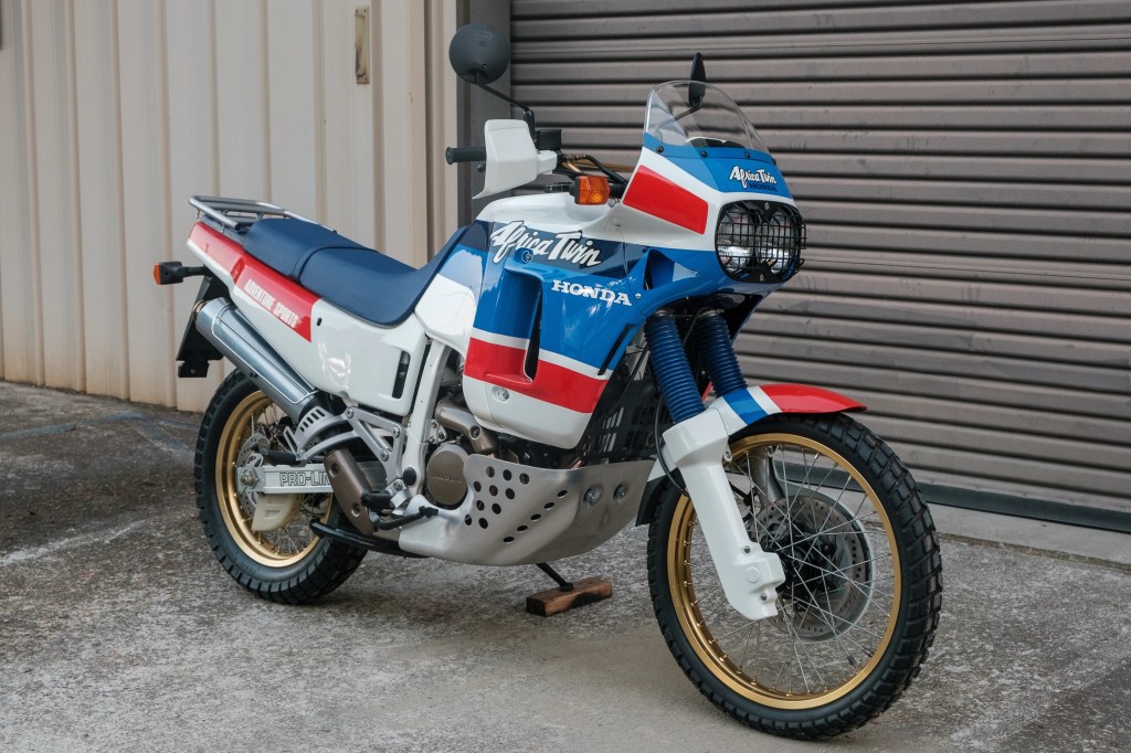 A white-blue-and-red 1989 Honda Africa Twin XRV650 in front of a garage