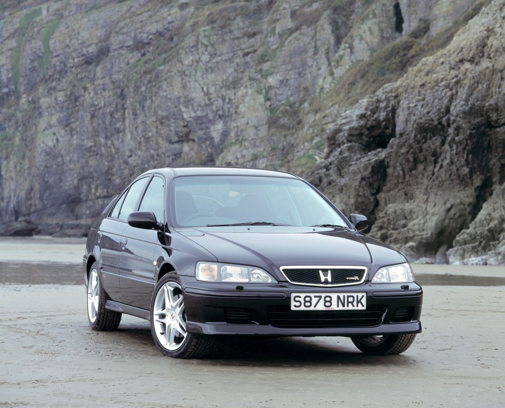 A black 1999 Honda Accord parked in front of beach side cliffs