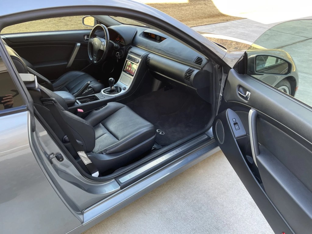 The black-leather front seats and aluminum-trimmed center console of a modified 2005 Infiniti G35 Coupe seen from the open door