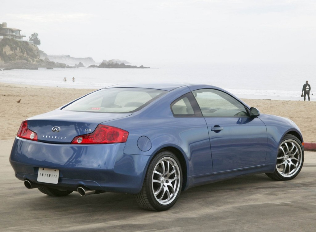 The rear 3/4 view of a blue 2005 Infiniti G35 Coupe parked by the beach