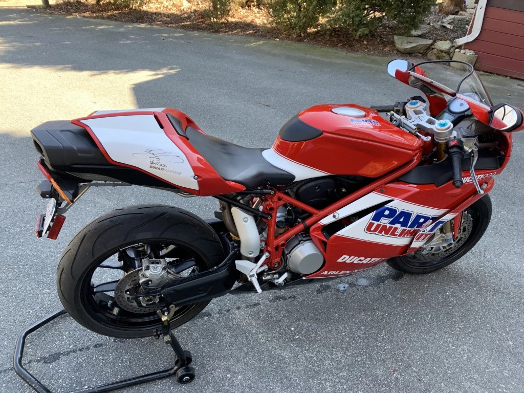 The overhead side 3/4 view of a red-white-and-blue-liveried 2007 Ducati 999S Team USA Edition on a rear-wheel stand in a driveway
