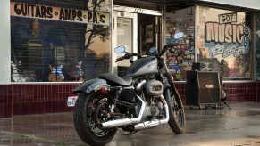 The rear 3/4 view of a gray-and-black 2012 Harley-Davidson Nightster parked by a record store