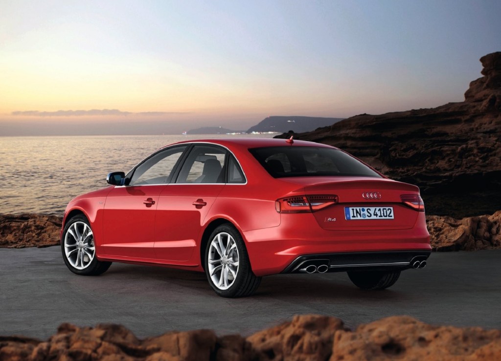 The rear 3/4 view of a red 2013 Audi S4 parked by some oceanside cliffs