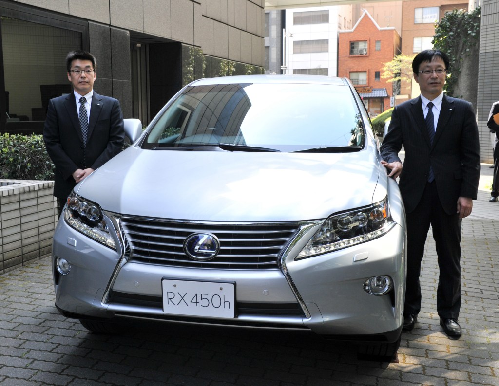 Japan's auto giant Toyota Motor managing officer Kazuo Ohara (R) introduces the company's newly designed Lexus RX 450h hybrid SUV with a 3.5-litre V6 engine
