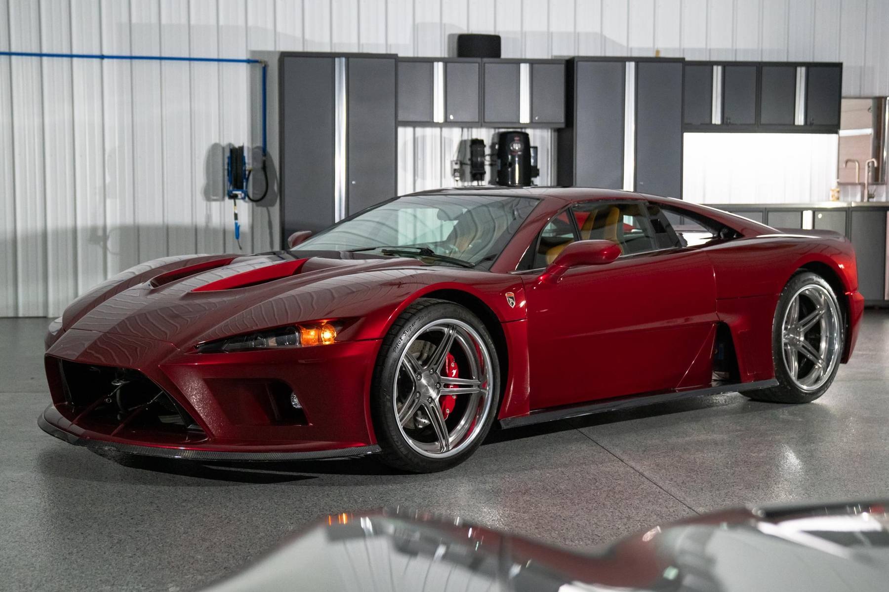 A maroon 2014 Falcon F7 parked in a car garage in front of a silver car