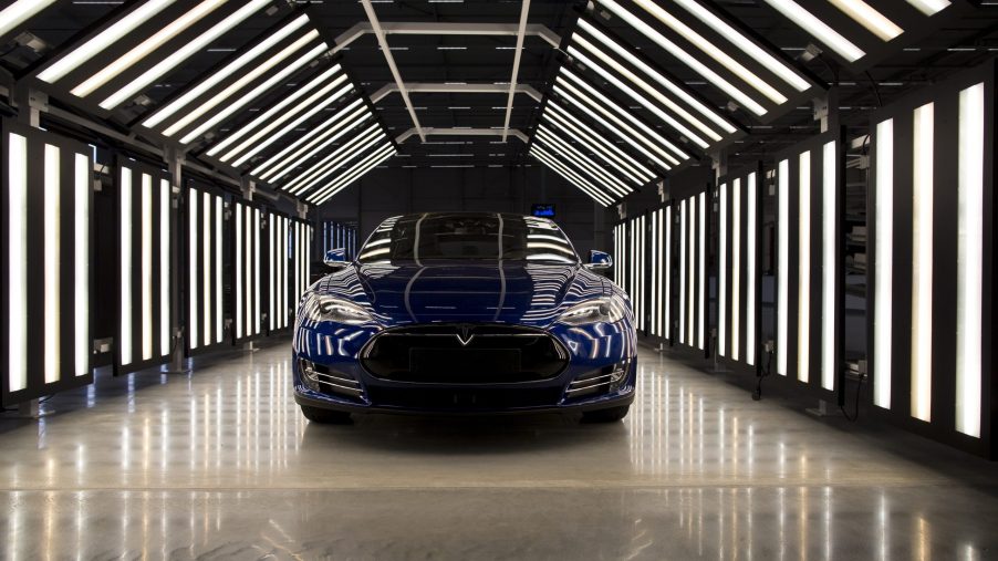 A blue 2015 Tesla Model S electric sedan under rows of lights