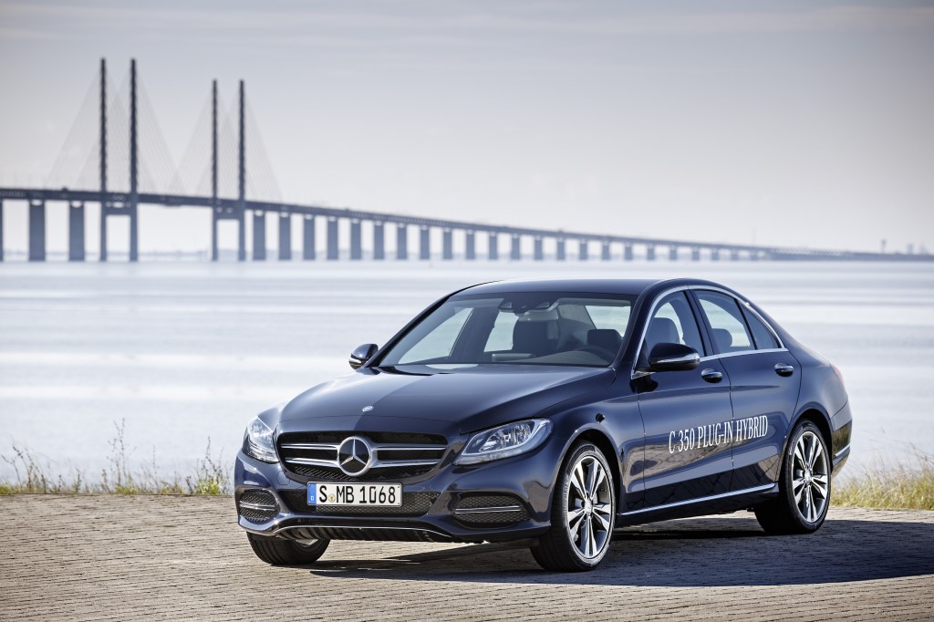A blue 2016 Mercedes-Benz C-Class (C350e) parked next to the water with a bridge in the background