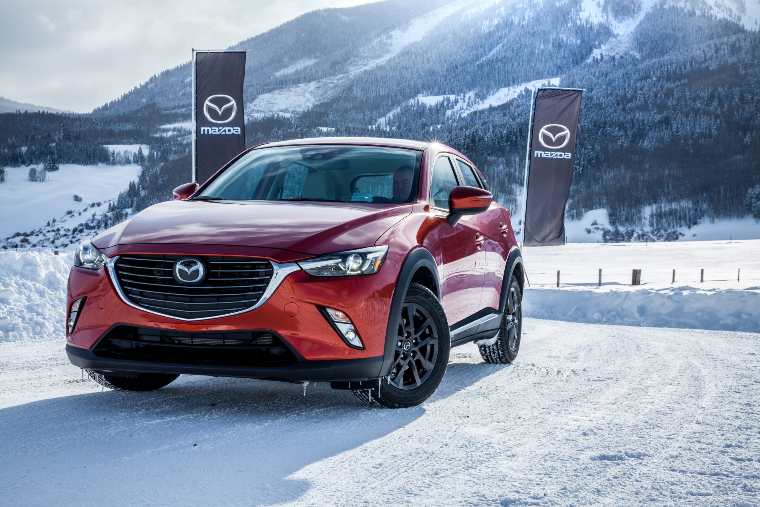 A red 2017 Mazda CX-3 parked in the show with Mazda flags in the background