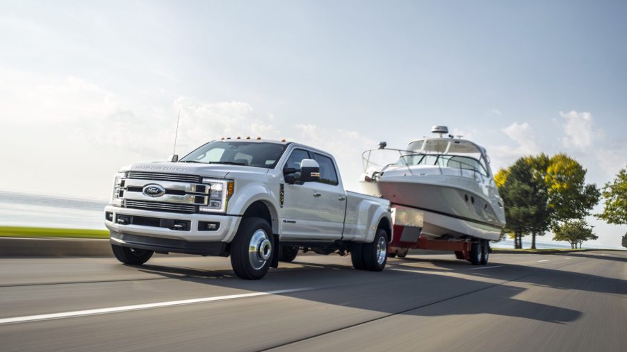 A white 2018 Ford Super Duty Limited towing a white boat on the highway