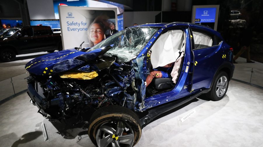A destroyed blue Honda SUV with a crash-test dummy inside