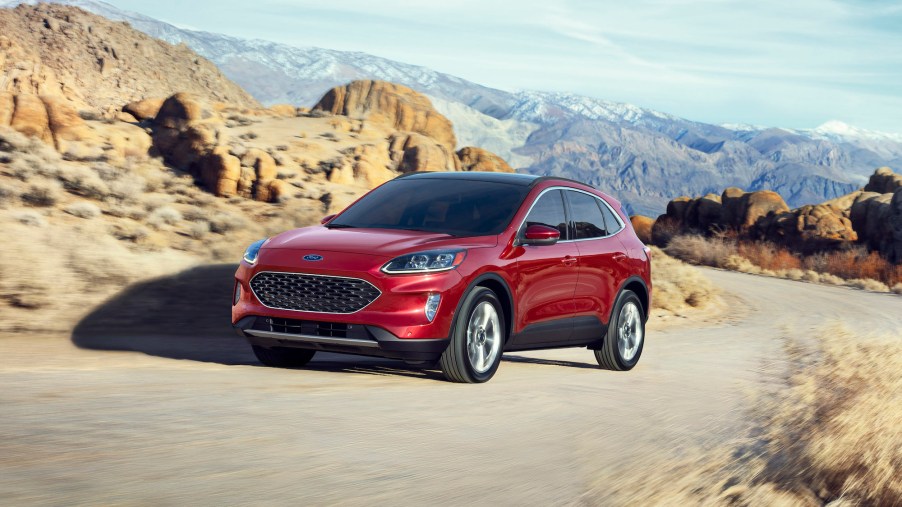 A red 2020 Ford Escape Hybrid compact SUV traveling on a narrow mountain road amid rocky terrain