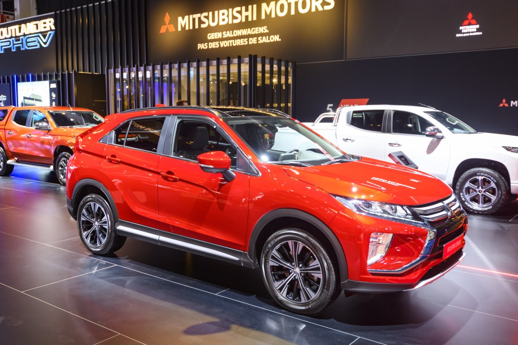 A red 2020 Mitsubishi Eclipse Cross on display at an auto show with some other SUVs in the background