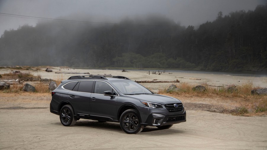 A dark-gray metallic 2020 Subaru Outback crossover SUV parked on a foggy shore