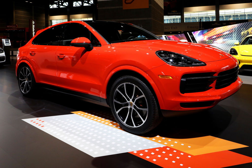A vibrant red 2020 Porsche Cayenne Coupe on display at an indoor show