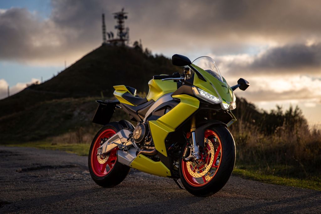 A highlighter-yellow 2021 Aprilia RS 660 parked by a hill at sunset