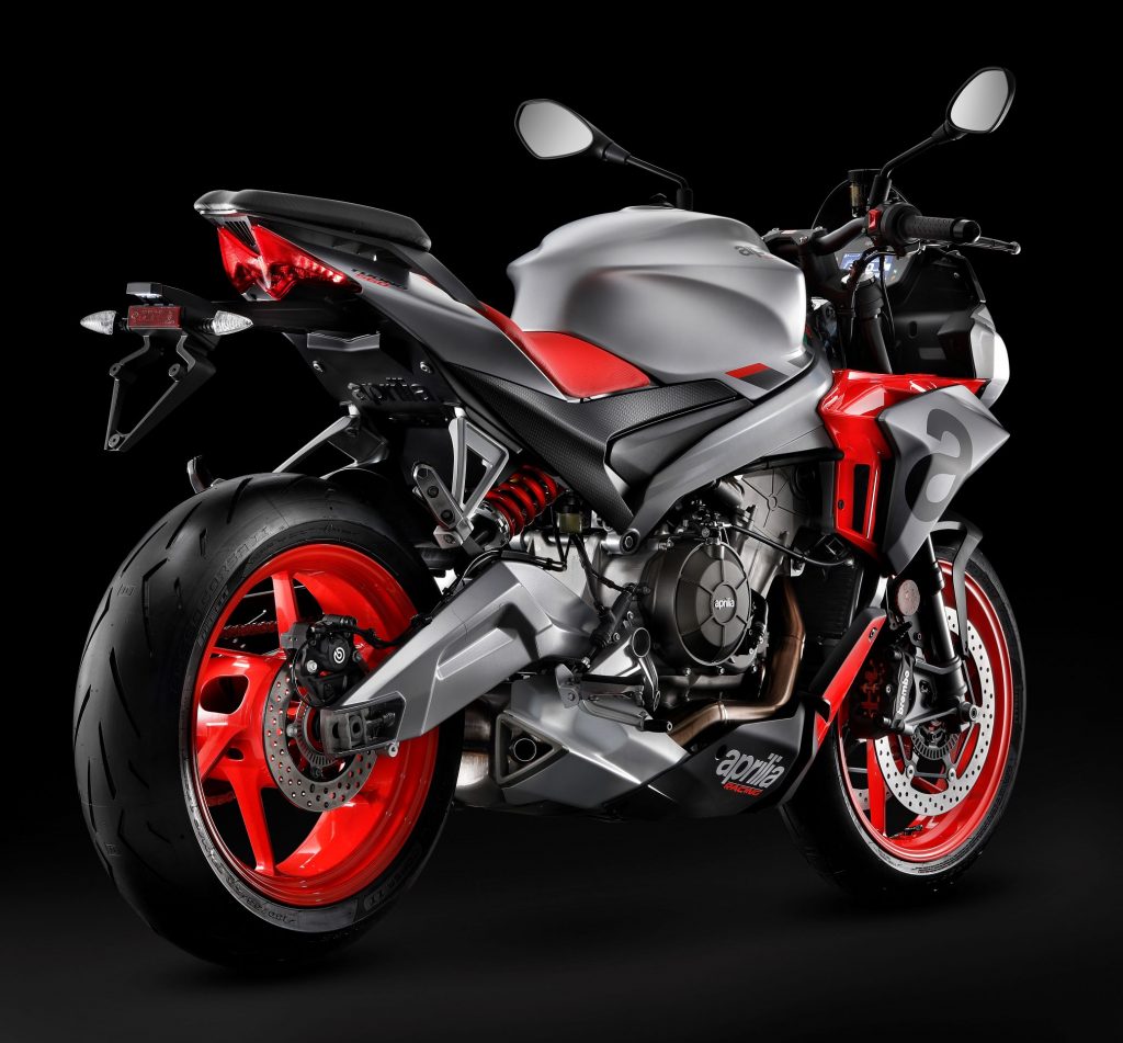 The rear 3/4 view of a silver-and-red 2021 Aprilia Tuono 660