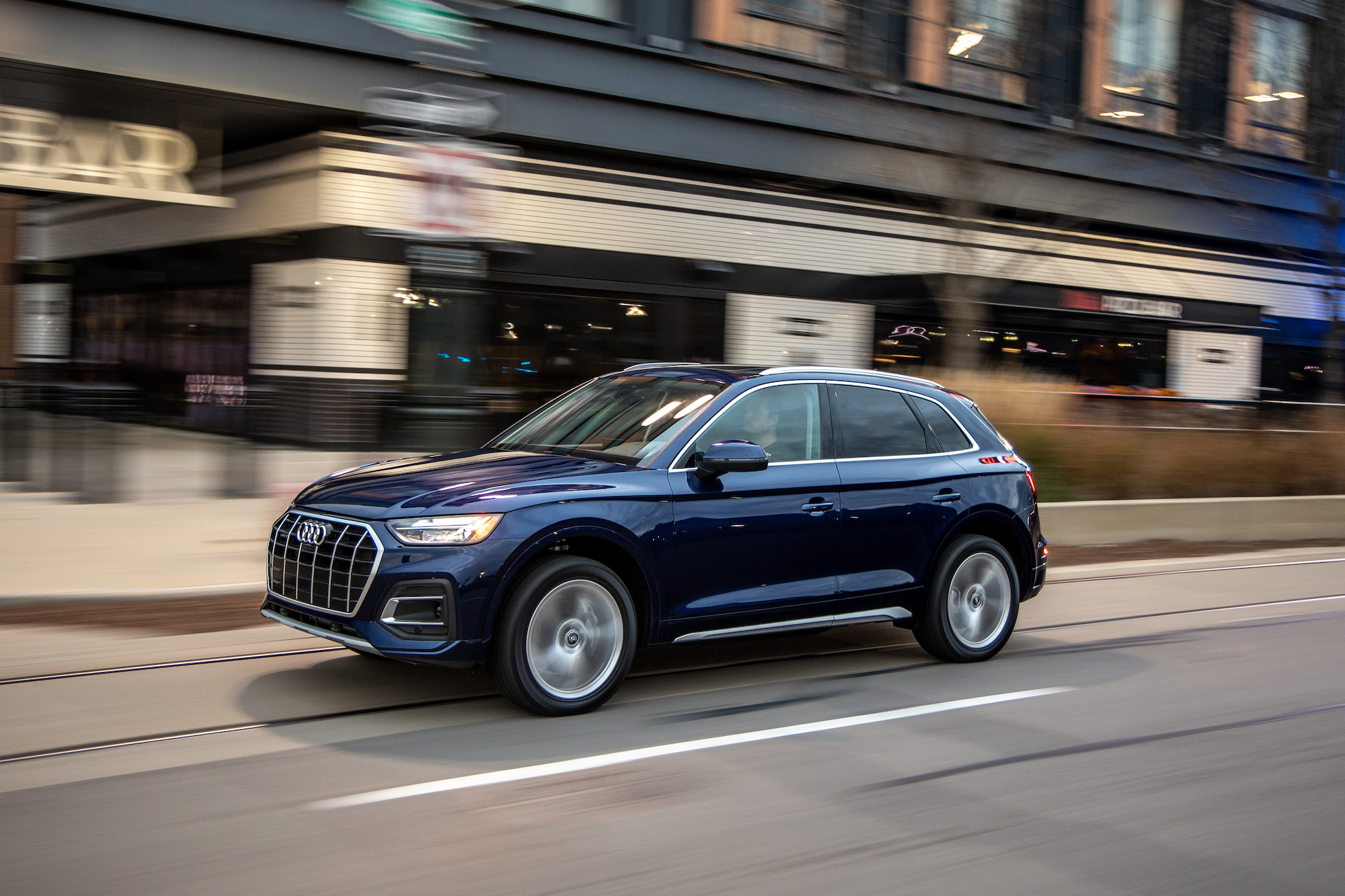 A dark-blue 2021 Audi Q5 compact SUV traveling on a city street