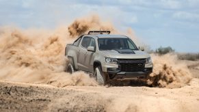 A grey and black 2021 Chevy Colorado ZR2 turbo-diesel pickup truck driving off-road, kicking up sand