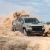 A grey and black 2021 Chevy Colorado ZR2 turbo-diesel pickup truck driving off-road, kicking up sand