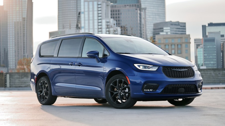A royal-blue 2021 Chrysler Pacifica Limited AWD, with black wheels and a black grille, parked in front of a cityscape