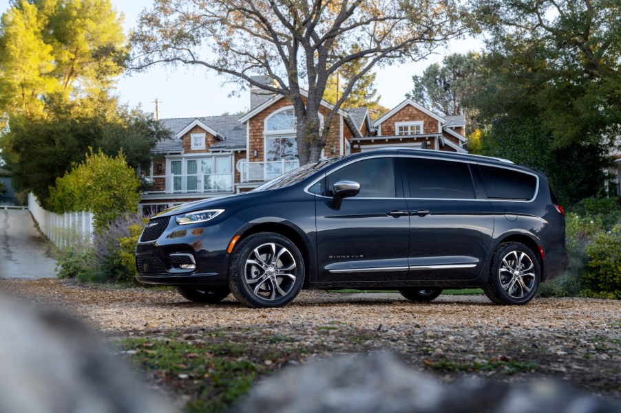 A dark-colored 2021 Chrysler Pacifica Pinnacle minivan parked outside a large shingled home