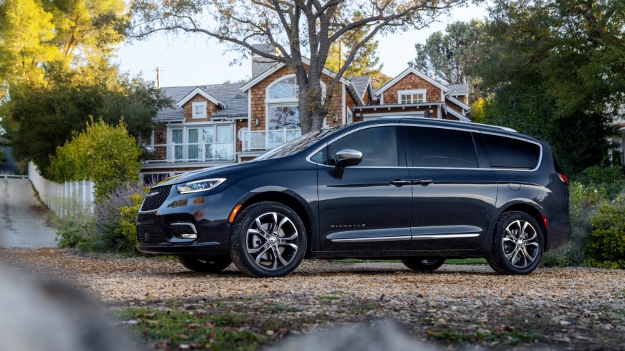 A dark-colored 2021 Chrysler Pacifica Pinnacle minivan parked outside a large shingled home
