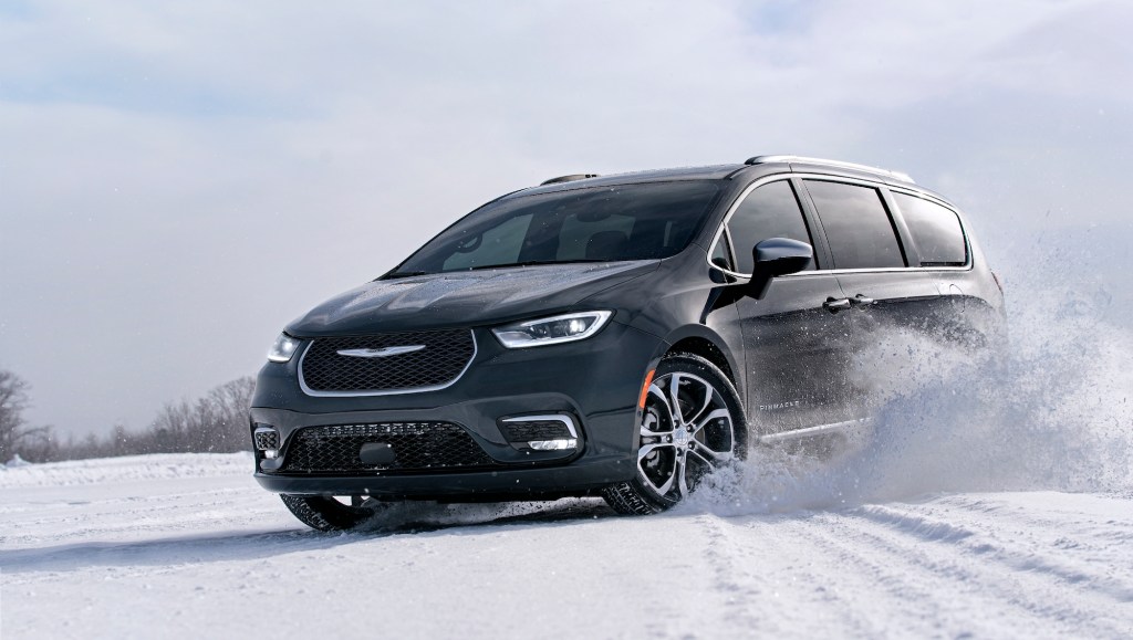 A dark-colored 2021 Chrysler Pacifica minivan drives in the snow