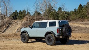 A four-door 2021 Ford Bronco SUV parked on a dirt trail near the woods