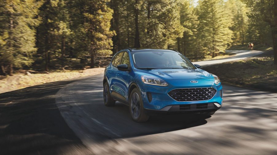 The 2021 Ford Escape in blue driving along a winding road with trees in the background