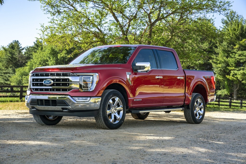 A red 2021 Ford F-150 Turbo-Diesel pickup truck parked on pavement with trees in the background