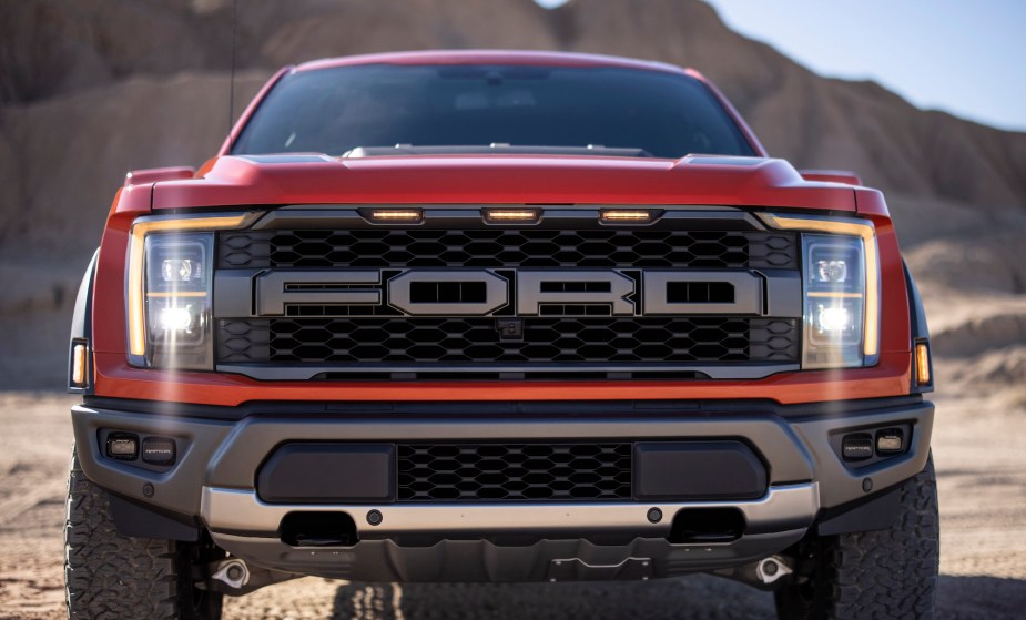 A close-up head-on view of a red 2021 Ford F-150 Raptor full-size pickup truck parked in a mountainous dessert