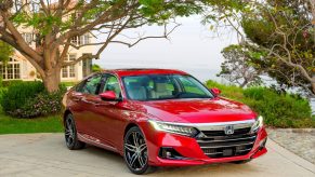 A red 2021 Honda Accord Hybrid parked in a driveway with trees surrounding it