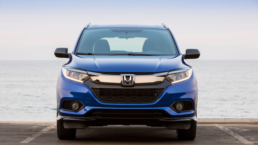 A blue 2021 Honda HR-V subcompact crossover SUV sitting in a parking space in front of an ocean