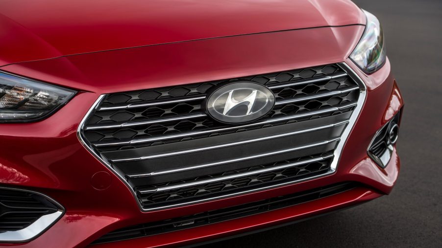 A close-up of the Hyundai logo on the grille of a red 2021 Accent subcompact car