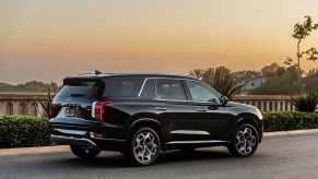 A black 2021 Hyundai Palisade three-row midsize SUV parked along a concrete rail overlooking hills and trees