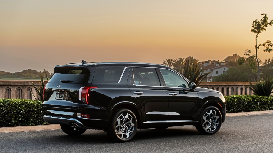 A black 2021 Hyundai Palisade three-row midsize SUV parked along a concrete rail overlooking hills and trees