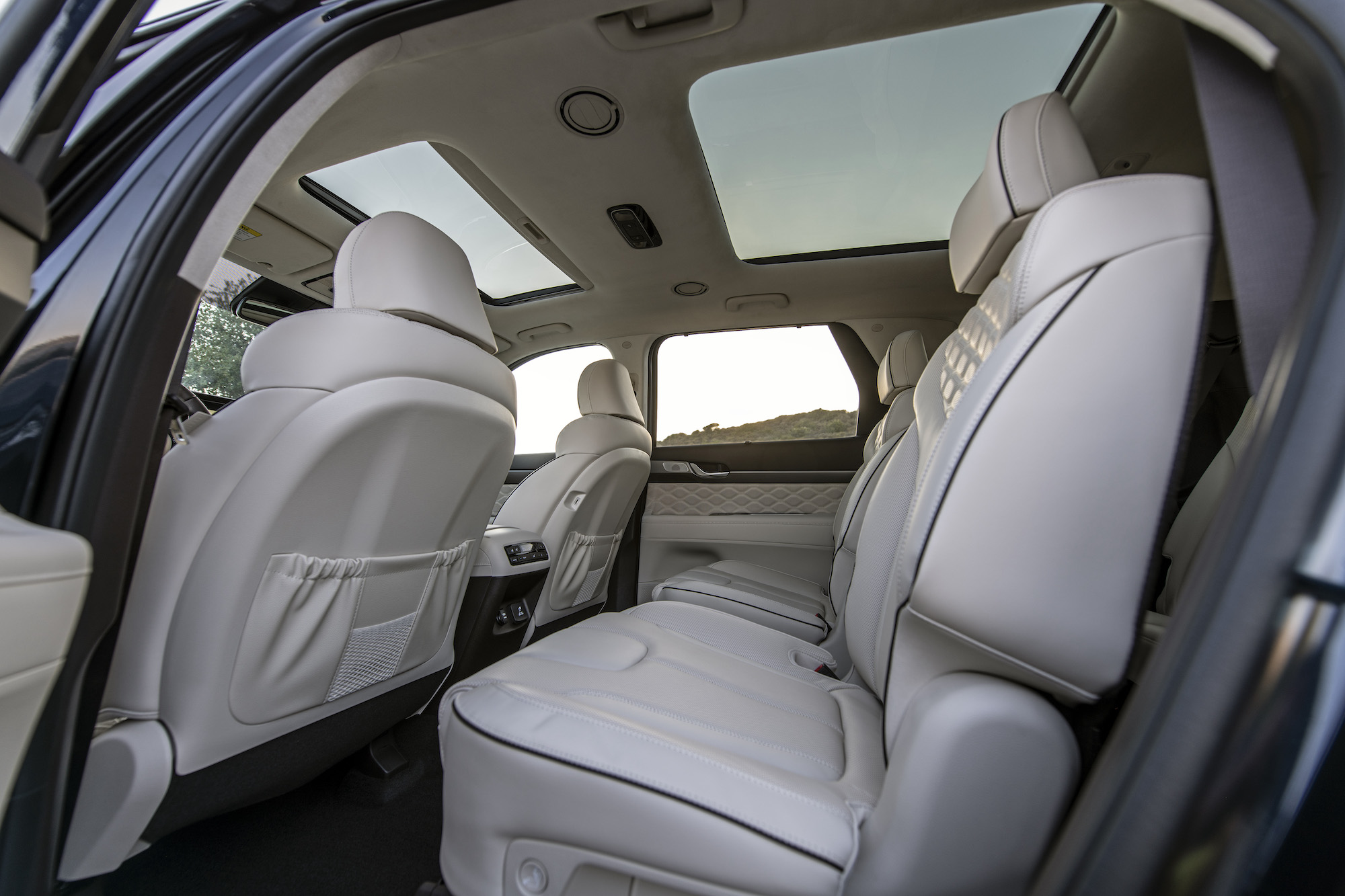 The interior of a 2021 Hyundai Palisade midsize crossover SUV with two moonroofs and quilted white leather seats