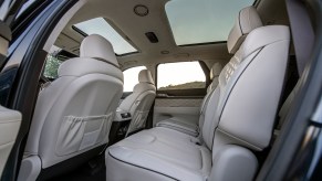 The interior of a 2021 Hyundai Palisade midsize crossover SUV with two moonroofs and quilted white leather seats