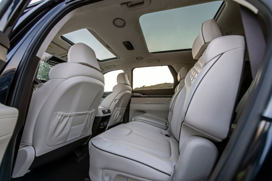 The interior of a 2021 Hyundai Palisade midsize crossover SUV with two moonroofs and quilted white leather seats