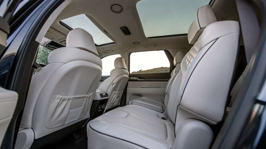 The interior of a 2021 Hyundai Palisade midsize crossover SUV with two moonroofs and quilted white leather seats