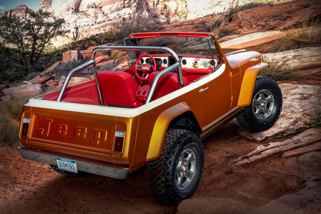 The rear 3/4 view of the orange 2021 Jeep Jeepster Beach concept crawling up a rocky desert trail