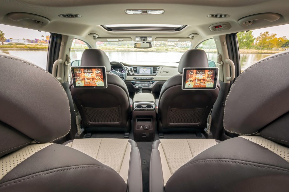 The brown and beige interior of a 2021 Kia Sedona minivan, shown from the third row looking forward