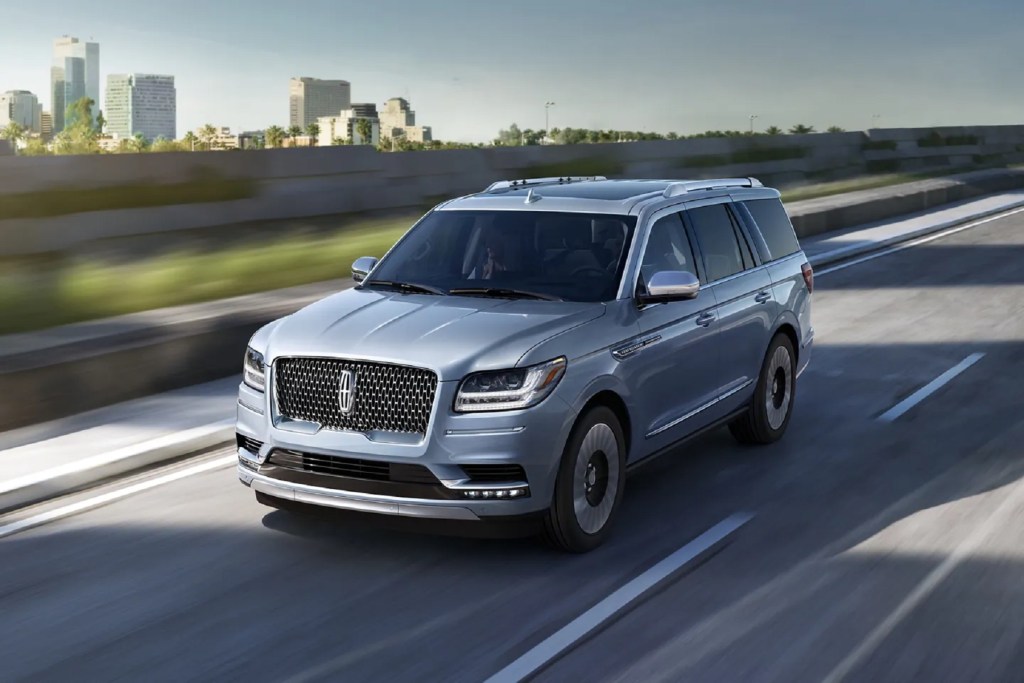 A pale-blue 2021 Lincoln Navigator Black Label SUV driving down the highway by a city