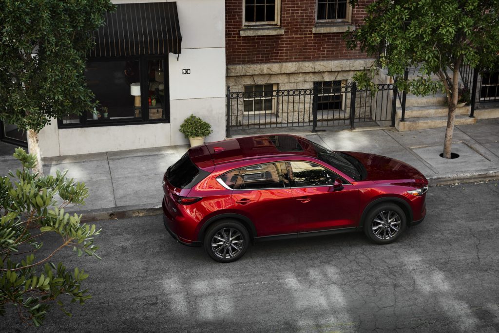A red 2021 Mazda CX-5 parked on a tree-lined city street