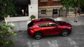 A red 2021 Mazda CX-5 parked on a tree-lined city street