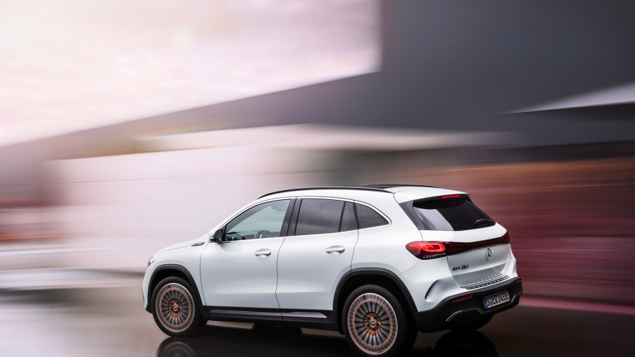 Computer rendering of a white 2021 Mercedes-Benz EQA250 electric crossover SUV with a blurred gray and brown background