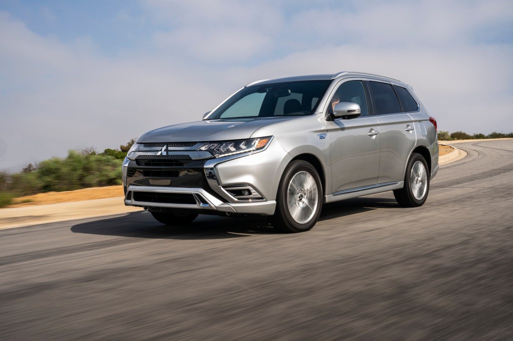 A silver 2021 Mitsubishi Outlander PHEV safely driving down a highway road